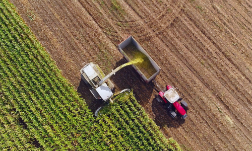 An arial view of a tractor in a field harvesting crops.